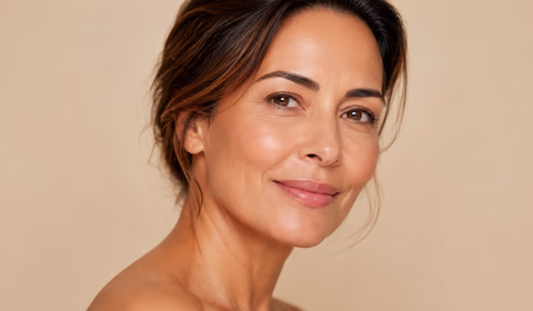 Close de rosto feminino com pele firme e iluminada, em fundo bege suave, representando resultados de bioestimuladores de colágeno