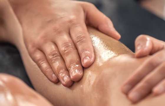 Profissional realizando drenagem linfática na perna de cliente em ambiente estético