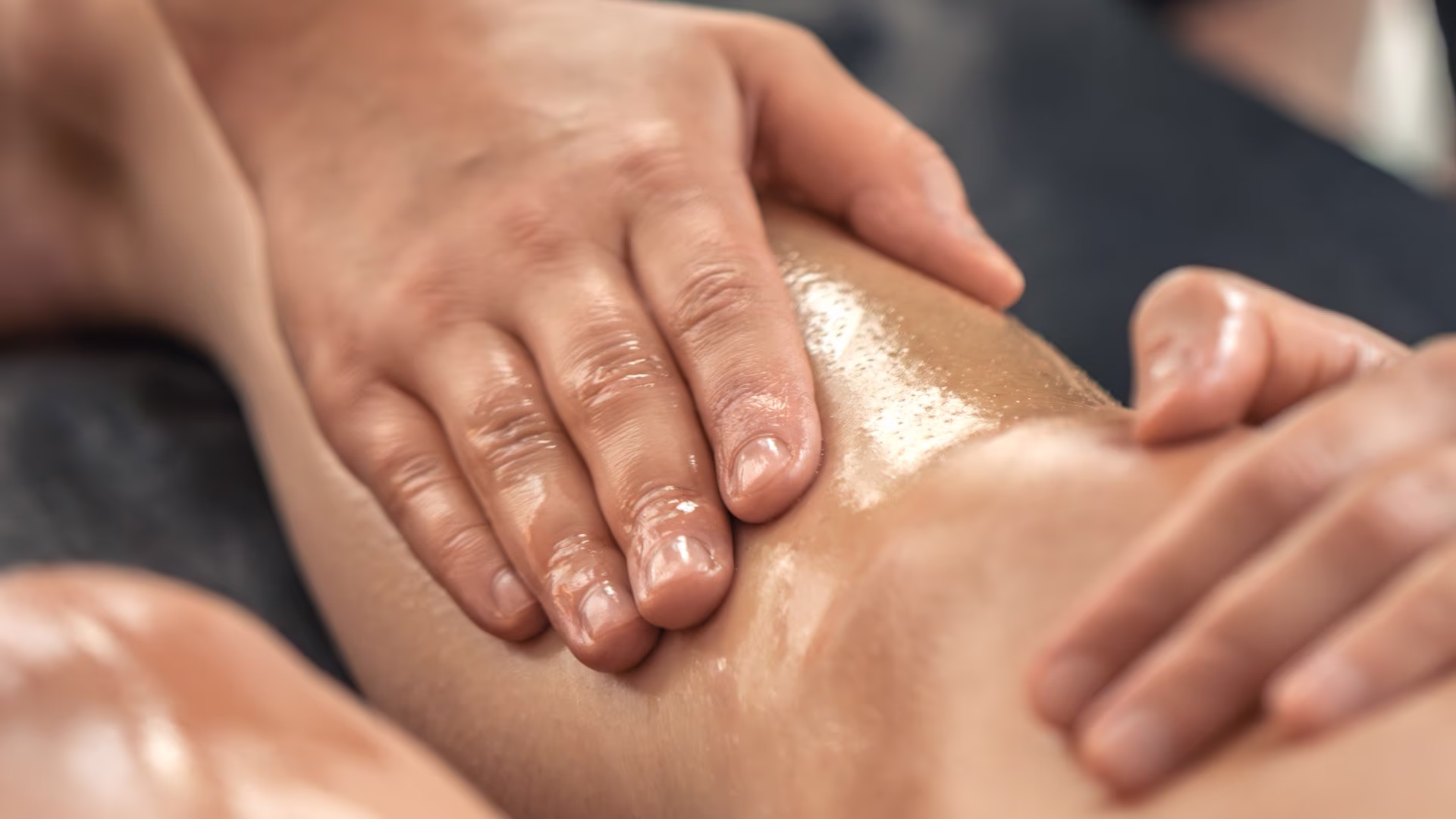 Profissional realizando drenagem linfática na perna de cliente em ambiente estético