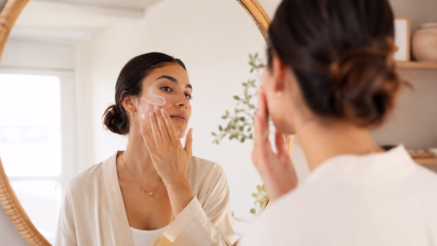 Mulher aplicando sérum cosmético no rosto diante do espelho, rotina de cuidado com GHK-Cu