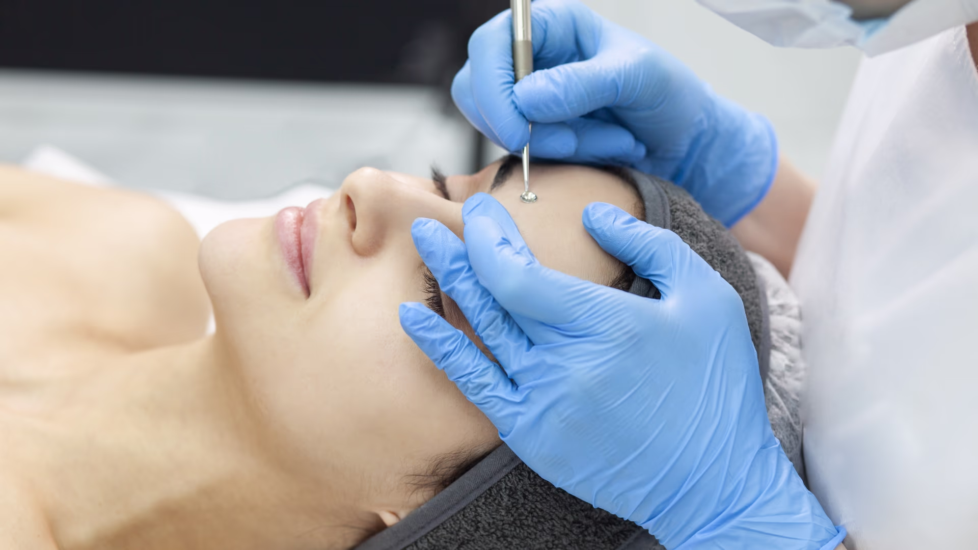 Profissional realizando limpeza de pele com instrumento esterilizado no rosto de cliente
