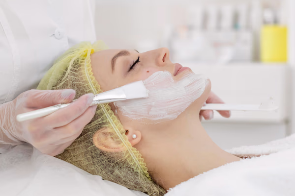 Profissional aplicando máscara facial durante peeling químico