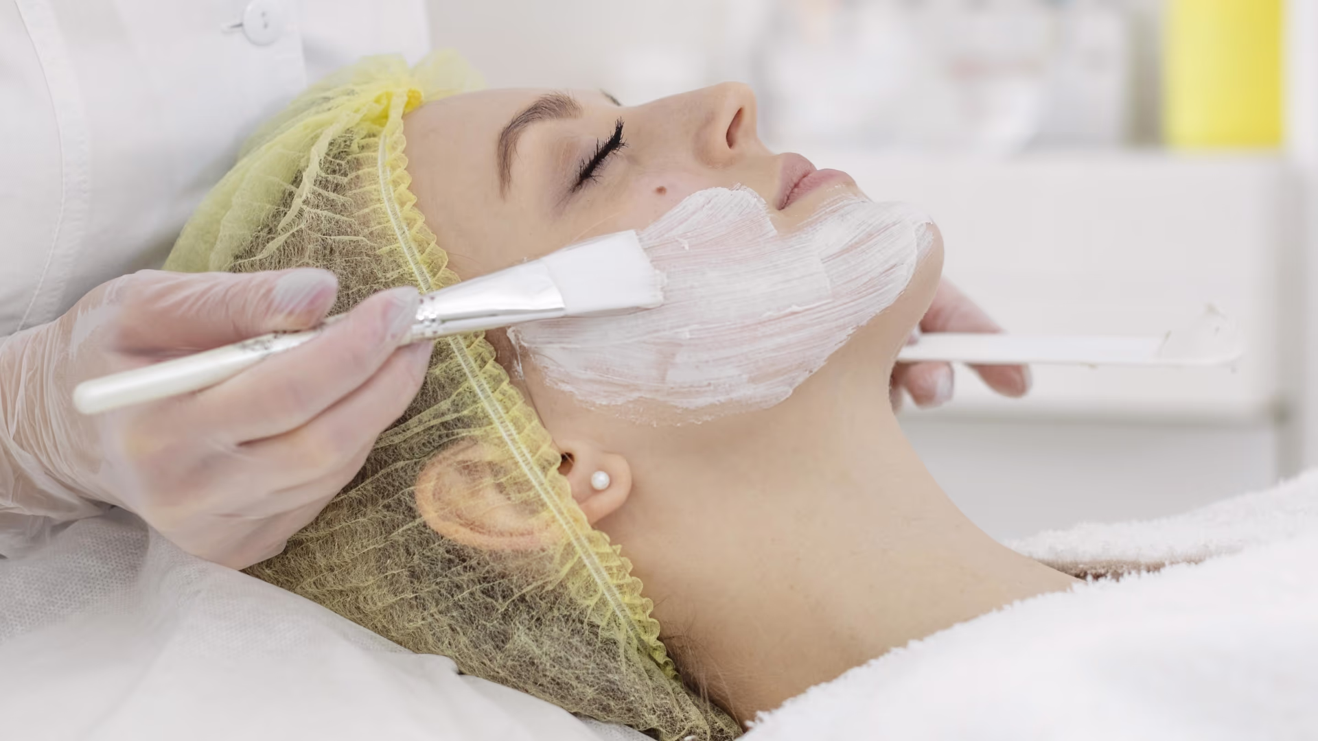 Profissional aplicando produto facial em cliente deitada, ilustrando renovação da pele com peeling químico