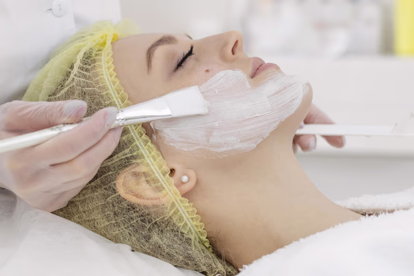 Profissional aplicando produto facial em cliente deitada, ilustrando renovação da pele com peeling químico