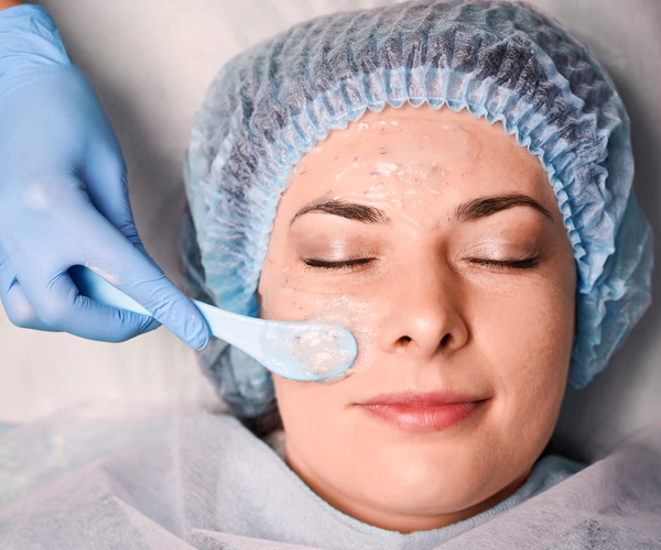 Peeling químico facial sendo aplicado com espátula por profissional em cliente deitada