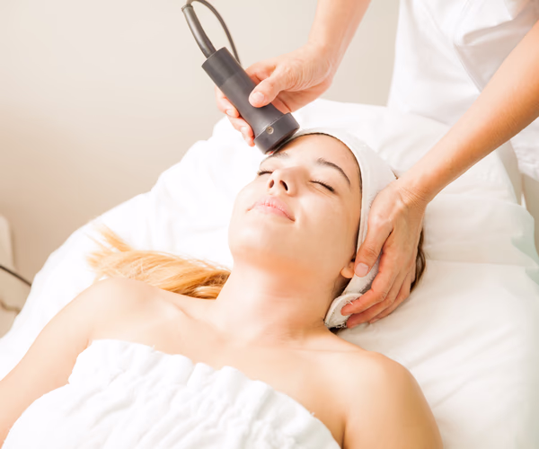Mulher recebendo tratamento de radiofrequência facial em clínica de estética.