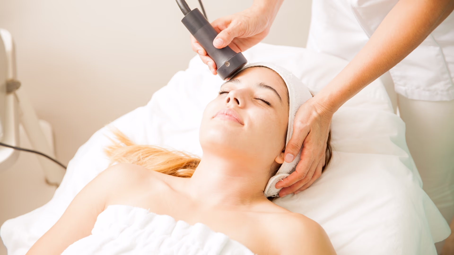 Mulher recebendo radiofrequência facial com aplicador em clínica de estética