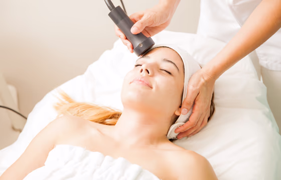 Mulher recebendo radiofrequência facial com aplicador em clínica de estética