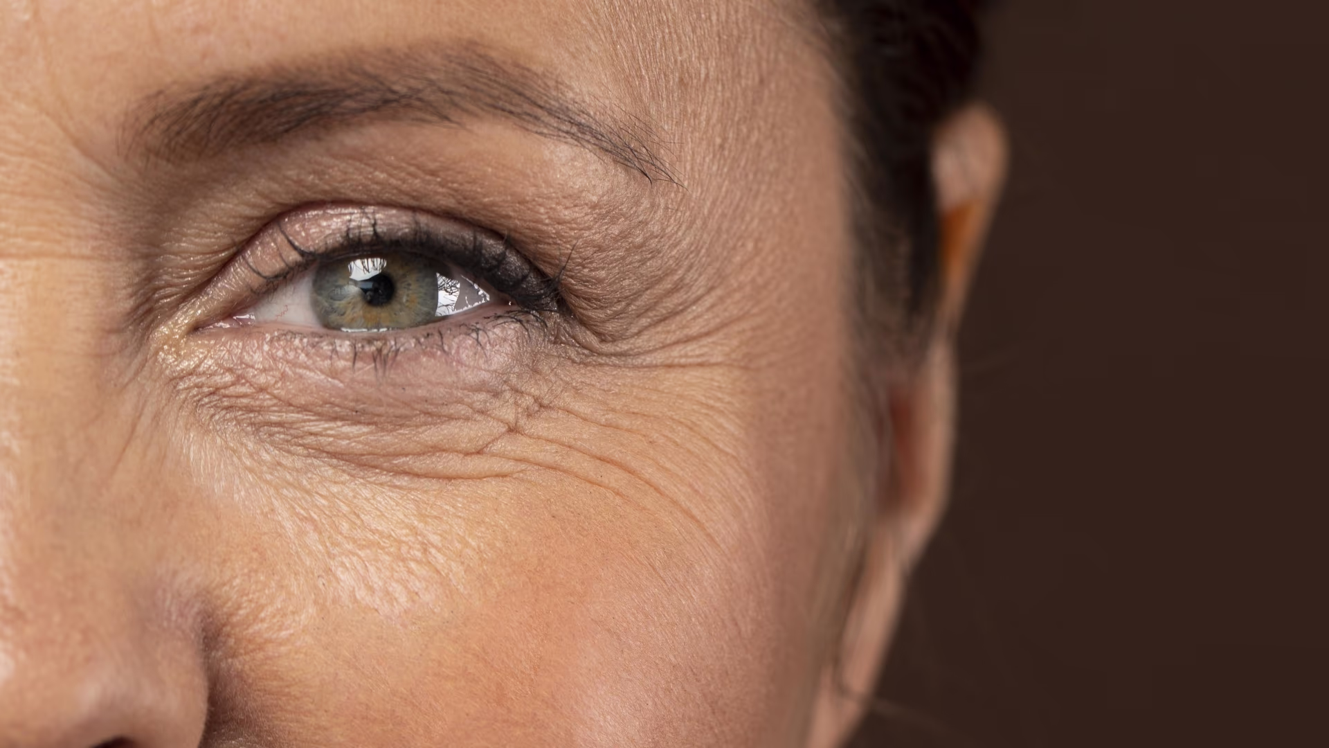 Close de metade do rosto de mulher madura com rugas naturais e pele iluminada