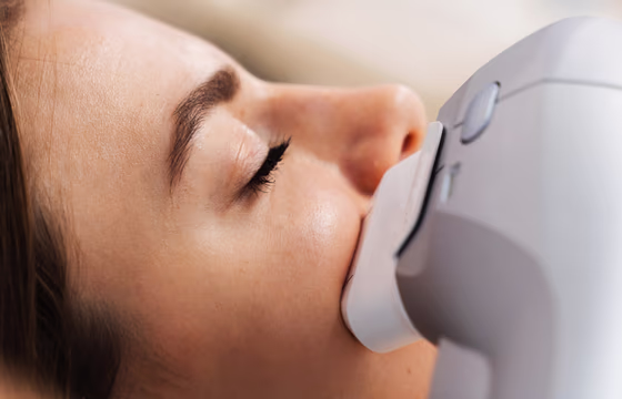 Aplicador de ultrassom microfocado posicionado no rosto de cliente deitada durante procedimento facial