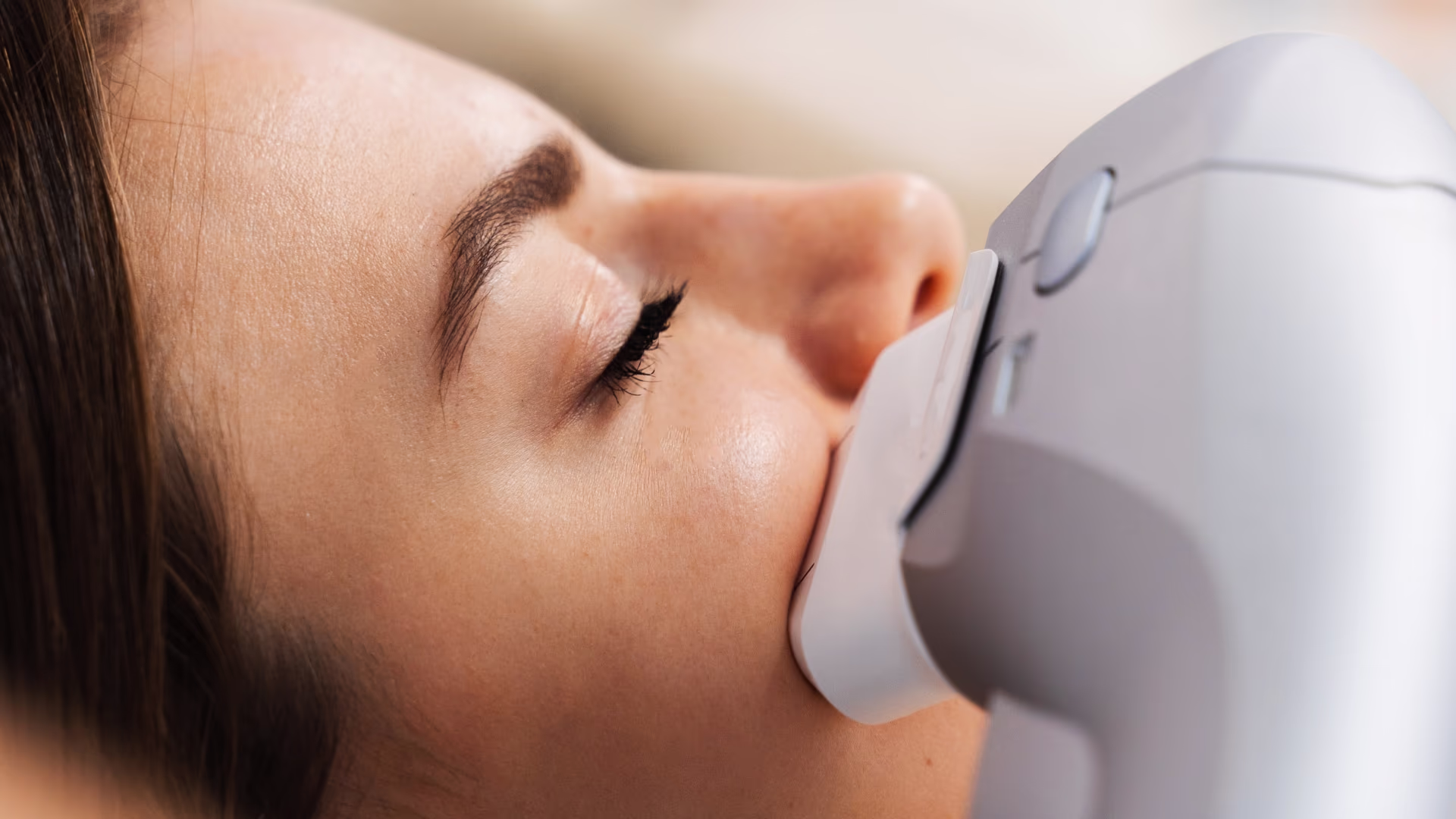 Aplicador de ultrassom microfocado posicionado no rosto de cliente deitada durante procedimento facial